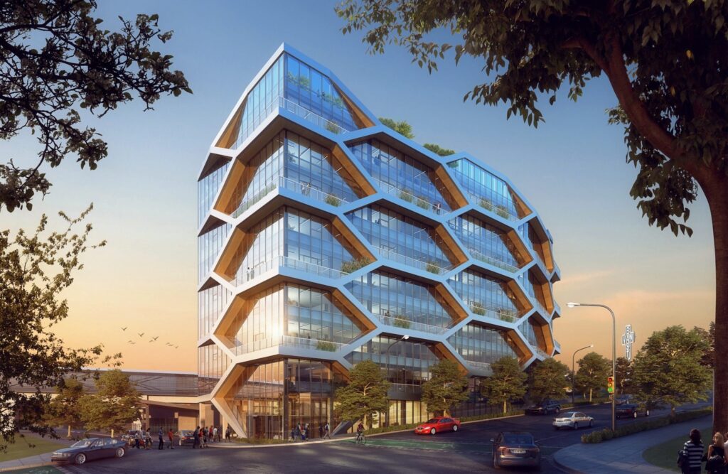 A modern, multi-story building with a distinctive honeycomb-like facade, surrounded by trees and street elements. Several cars and pedestrians are visible in the foreground.