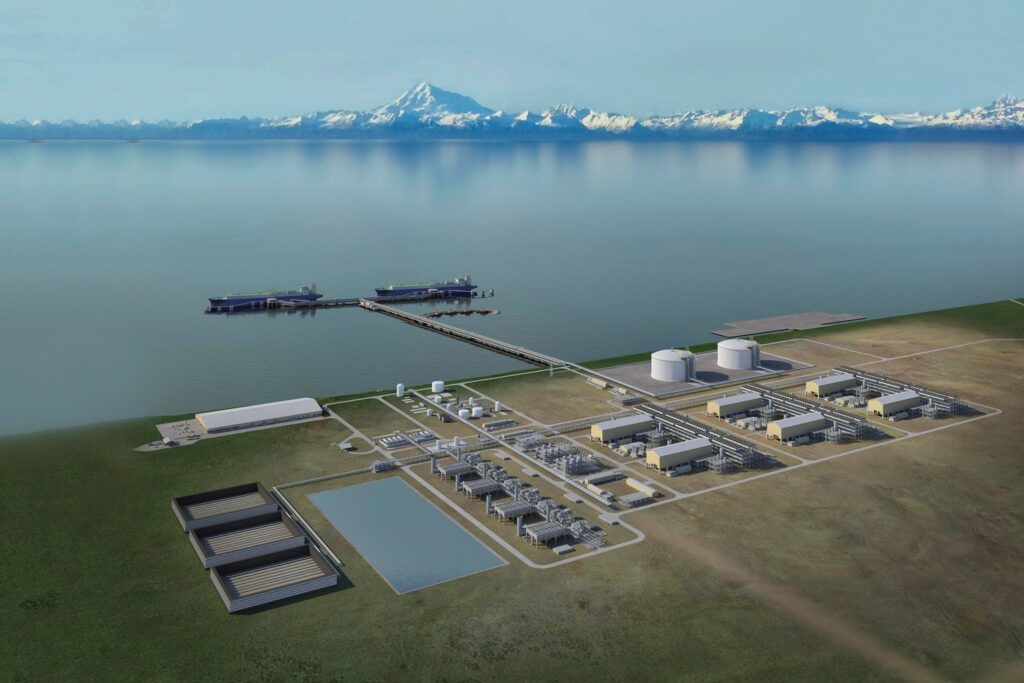 A coastal industrial facility with multiple buildings, storage tanks, and docks extending into the water, surrounded by flat land with a mountain range in the background.