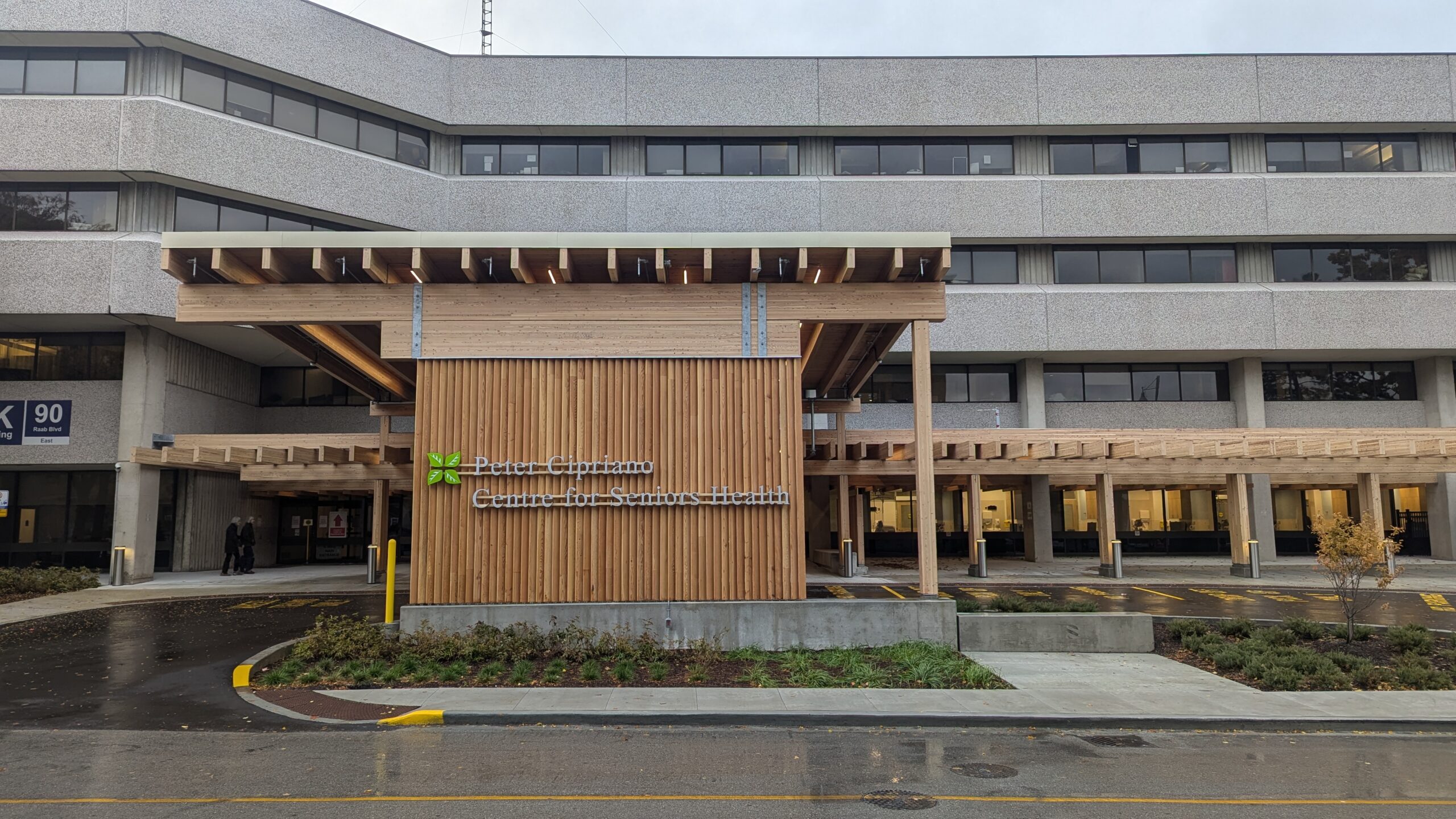 The exterior of the Peter Cipriano Centre, a modern building with timber paneling and a covered entrance. It was launched by Sunnybrook Health Sciences Centre.