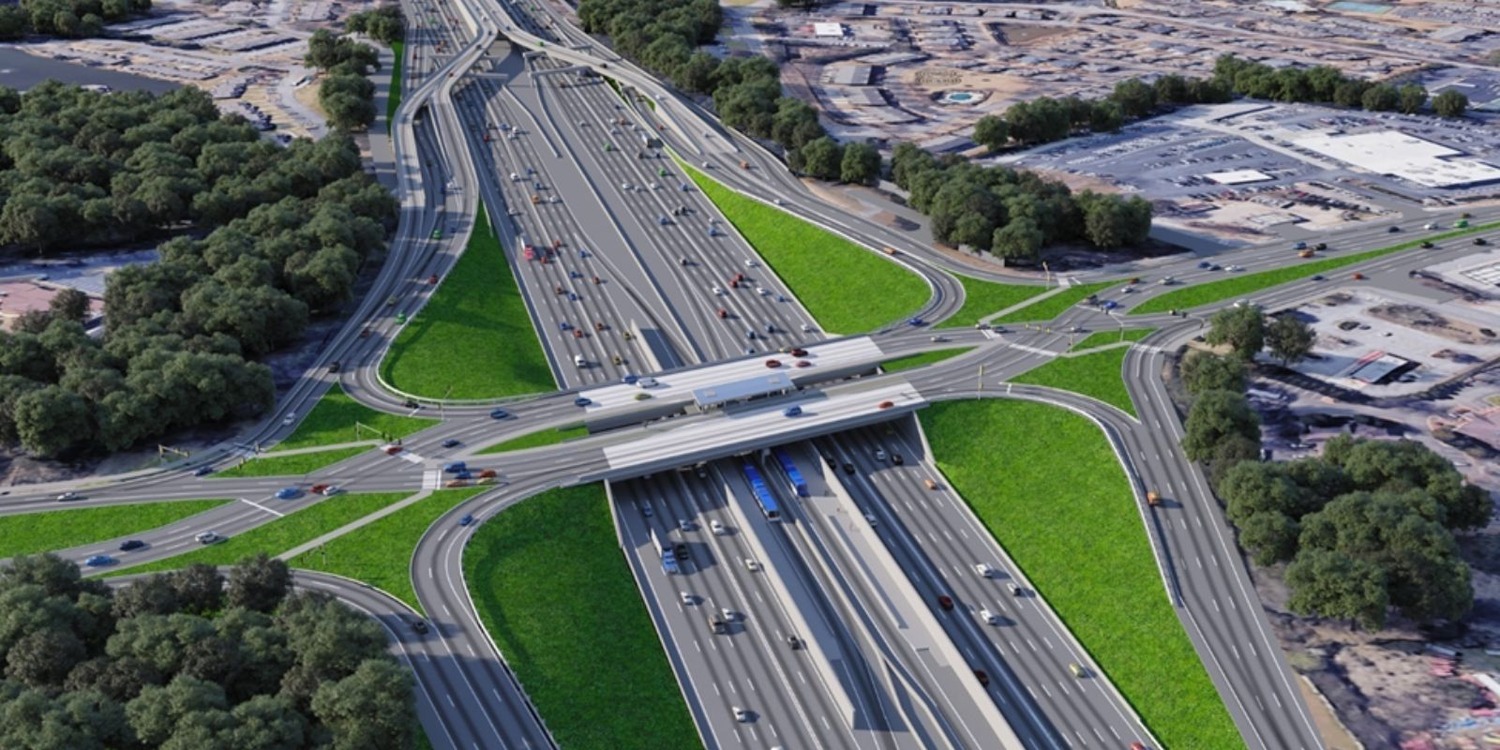 Aerial view of a highway interchange with SR 400 Express Lanes, multiple lanes, overpasses, cars, green medians, and surrounding trees and buildings.