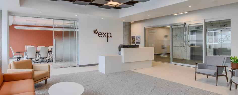 Modern office lobby with a reception desk, seating area, glass-walled conference room, and the company logo "exp." displayed on the wall.